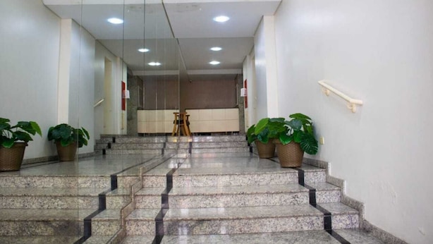 Un'accogliente hall d'albergo con una scalinata in marmo, piante in vaso e la reception.