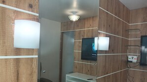 Un bagno moderno con pannelli in legno, un mobile lavabo bianco, uno specchio e un lampadario a soffitto.