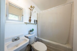 A bathroom with a bathtub, toilet, sink, and a mirror. - The Charmer, Super Close to UT + Downtown (Austin)