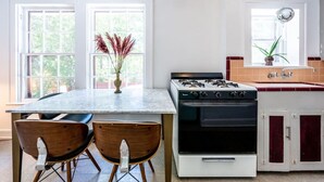 A kitchen with a central island, two chairs, a stove, and a sink. - The Charmer, Super Close to UT + Downtown (Austin)