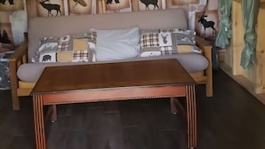 A wooden interior with a sofa and a bench, wooden beams on the ceiling, and animal silhouettes on the wall. - Enjoy nature in a cabin getaway, wildflowers, lush fields and maple woods trails (Cambridge)