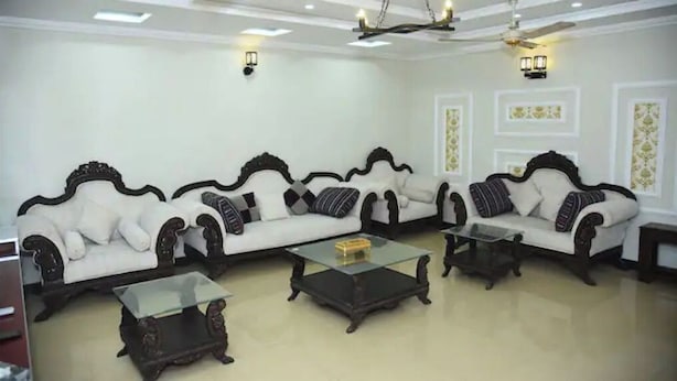 Ein Wohnzimmer mit zwei weißen Sofas, schwarzen und weißen Kissen, einem Glastisch und einem Deckenventilator.