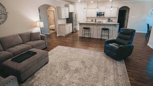 A modern kitchen with white cabinets, a central island, and pendant lights. - Spark Getaways: The Ricardo (Lubbock)