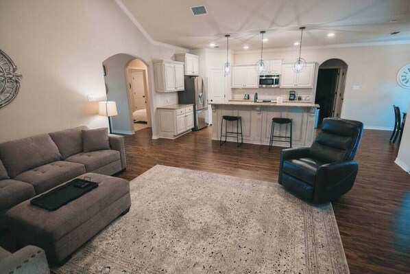 A modern kitchen with white cabinets, a central island, and pendant lights.