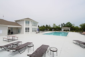 A pool area with lounge chairs and a building with a flag.