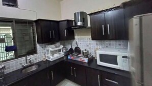 A kitchen with dark cabinets, a microwave, a gas stove, and a window with bars.