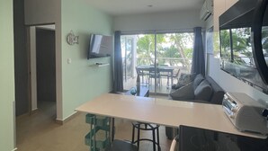 A modern kitchen with a built-in oven, a dining area with a table and chairs, and a large window offering a view of palm trees. - NEW OCEAN FRONT CONDO 2BR 2BATH full amenities (Bejuco)