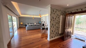 A spacious living area with a grey sofa, wooden flooring, and patterned wallpaper. - Casa Roc Madeira | 5 Bedrooms | Ocean and City Views, Private Heated Pool (Funchal)