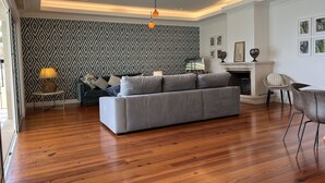A modern living room with a grey sofa, wooden flooring, patterned wallpaper, and a fireplace. - Casa Roc Madeira | 5 Bedrooms | Ocean and City Views, Private Heated Pool (Funchal)