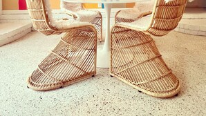 A room with a white table and four wicker chairs with white fur throws. A colorful wall with various shades of squares is behind the table. - Coligny Retro Beach House Ocean access, Pool, Grill, Kids Room! (Hilton Head Island)