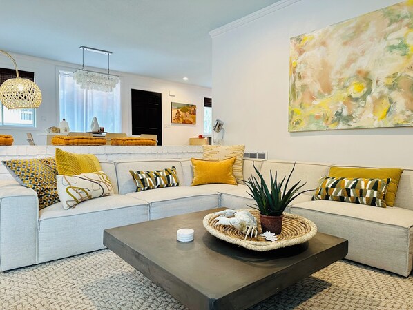 A modern living room with a sectional sofa, a coffee table, and a large abstract painting.