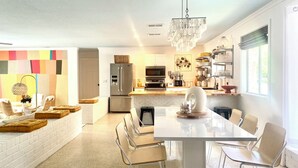 A modern kitchen with a central island, stainless steel appliances, and a chandelier. - Coligny Retro Beach House Ocean access, Pool, Grill, Kids Room! (Hilton Head Island)