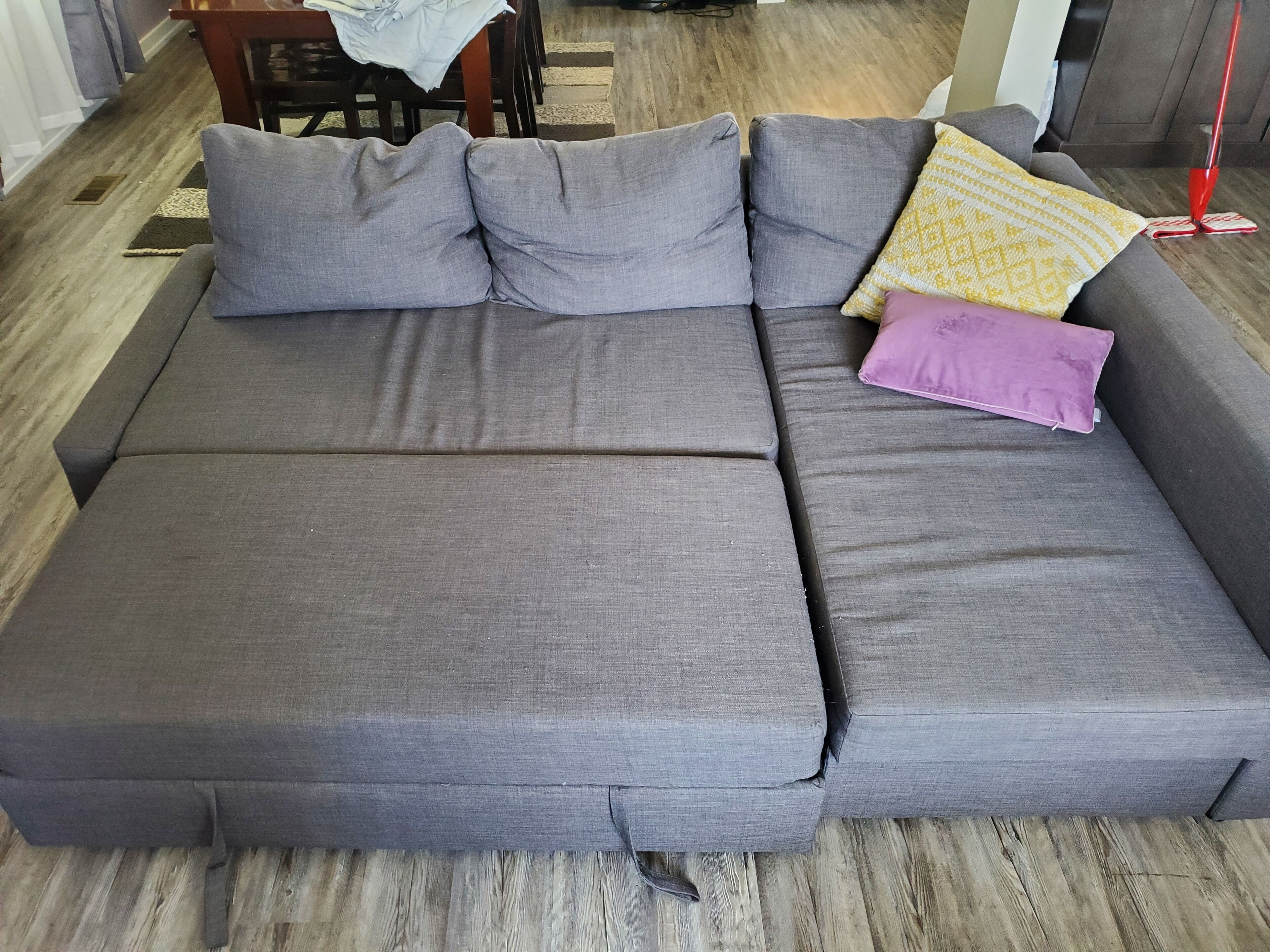 Un sofá seccional gris con varios cojines y una mesita con un mantel.
