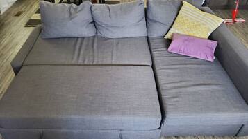 Un sofá seccional gris con varios cojines y una mesita con un mantel.