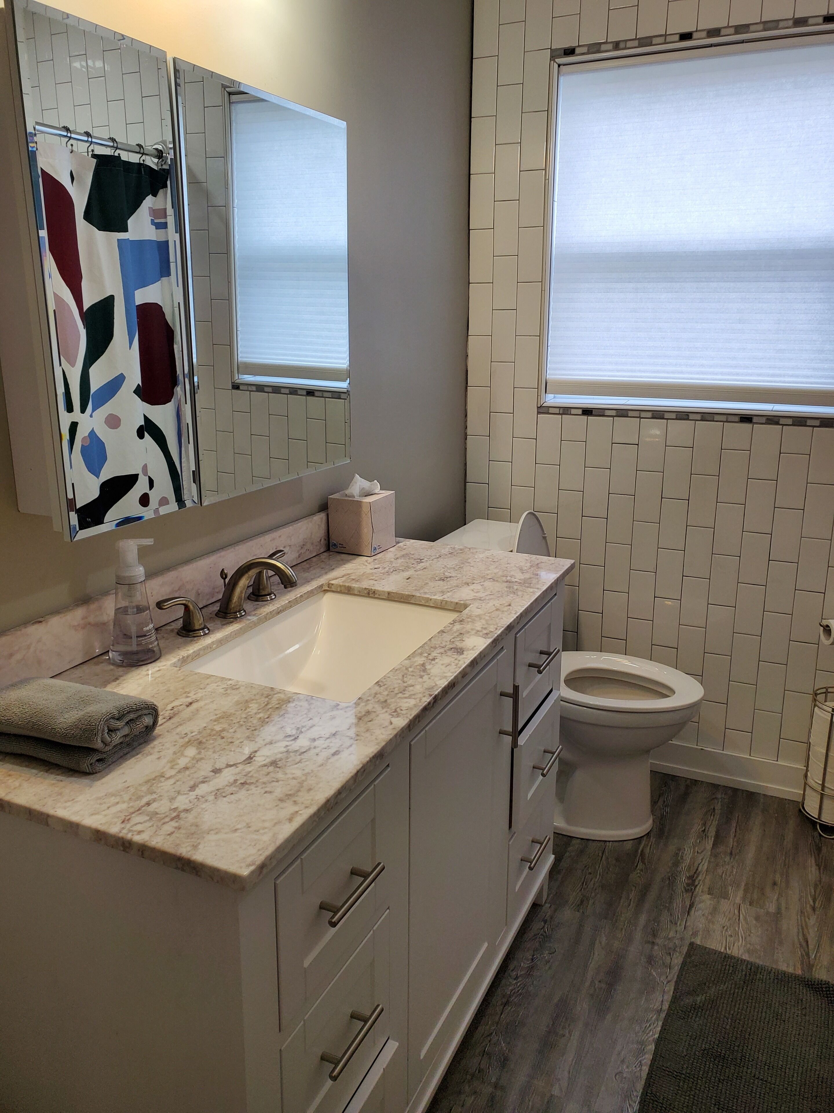 Een badkamer met een marmeren wastafel, toilet en douche.