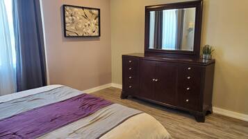 Een slaapkamer met een bed, een dressoir, een spiegel en een schilderij aan de muur.