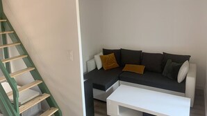 A living room with a green staircase, a grey sofa with cushions, and a white coffee table. - House in Les Issambres 10 minutes walk from the beach (LES ISSAMBRES)