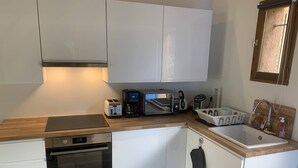 A compact kitchen with white cabinets, a built-in oven, a microwave, a toaster, and a sink. - House in Les Issambres 10 minutes walk from the beach (LES ISSAMBRES)