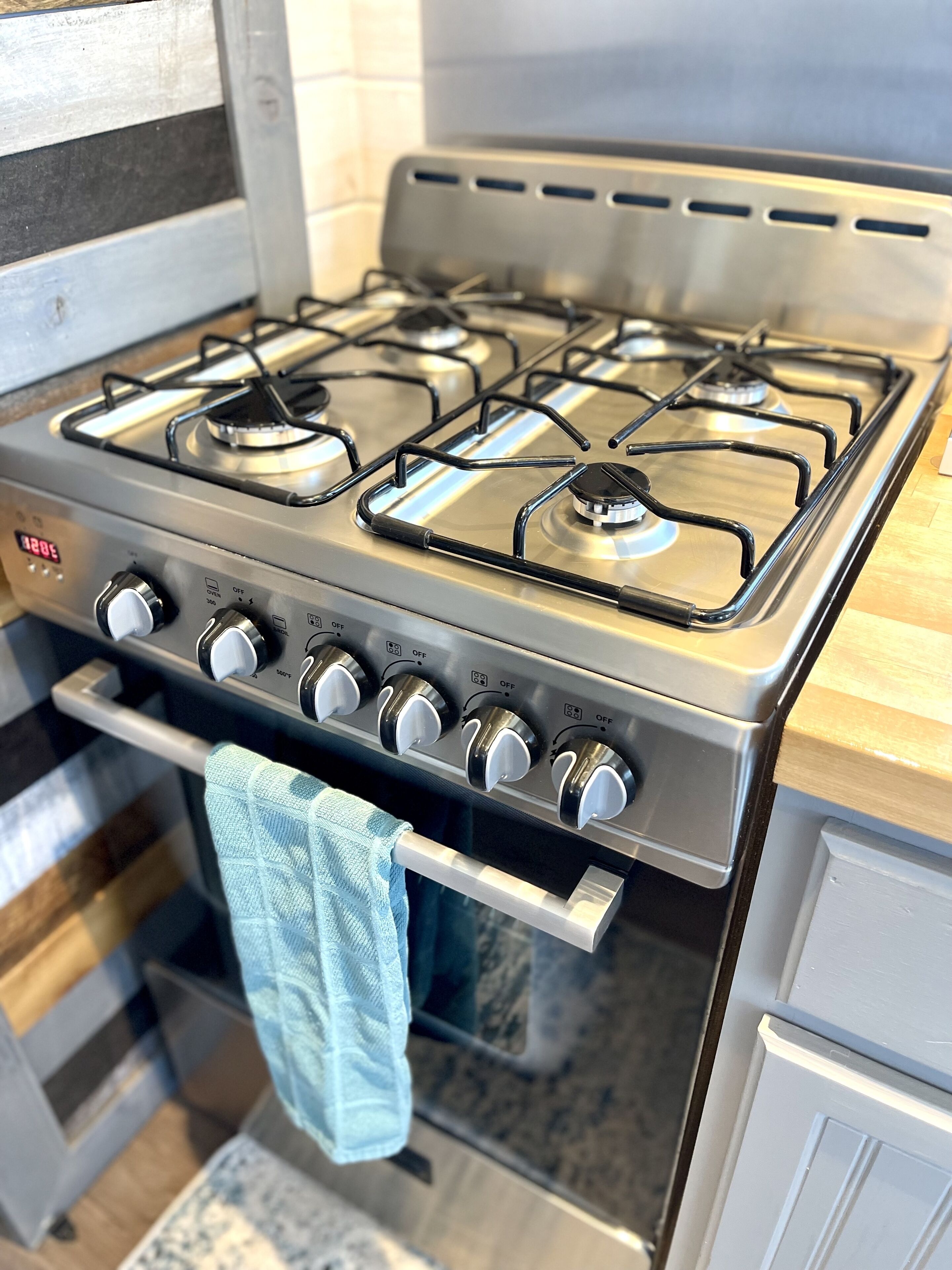 Une cuisinière à gaz en acier inoxydable, dotée de quatre brûleurs et d’un panneau de commande avec plusieurs boutons.