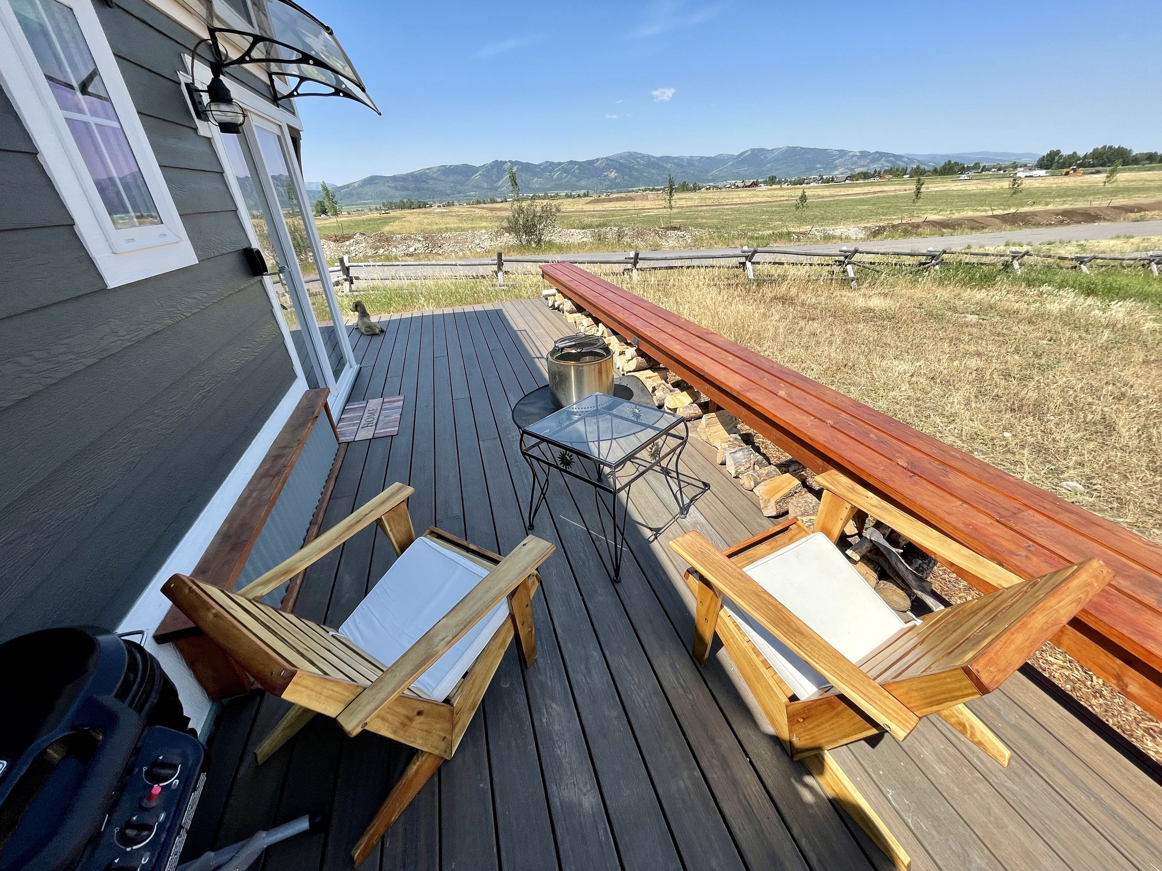Una terrazza con mobili in legno, un tavolo e una sedia in metallo.
