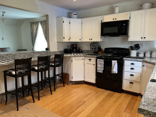 A kitchen with white cabinets, a black stove, a microwave, and a granite countertop. - Golf, Ski, Hike great for wedding guests (Roxbury)