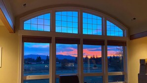 A room with large arched windows offering a view of a sunset over a mountainous landscape. - Enumclaw Estate, Scenic Views! Sleeps12,HotTub,Sauna, 1hr frm Rainier & Crystal (Enumclaw)