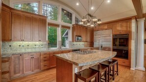 A spacious kitchen with wooden cabinets, a granite countertop, and stainless steel appliances. - Enumclaw Estate, Scenic Views! Sleeps12,HotTub,Sauna, 1hr frm Rainier & Crystal (Enumclaw)