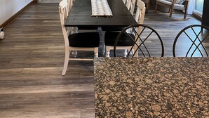 Un comedor amplio con una mesa larga, sillas blancas y una pared de acento de piedra.