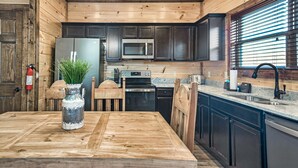 A wooden interior with a kitchen area featuring dark cabinets, a stainless steel refrigerator, a microwave, and a sink.