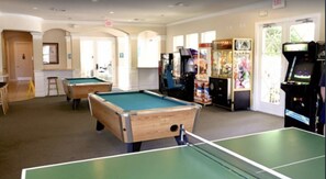 A recreational area with pool tables, arcade games, and a ping pong table.
