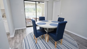 Un coin repas avec une table ronde, des chaises à revêtement bleu et un tapis à motifs.