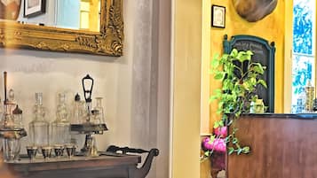 A vintage-style room with a wooden table, a large ornate mirror, and a decorative ceiling.