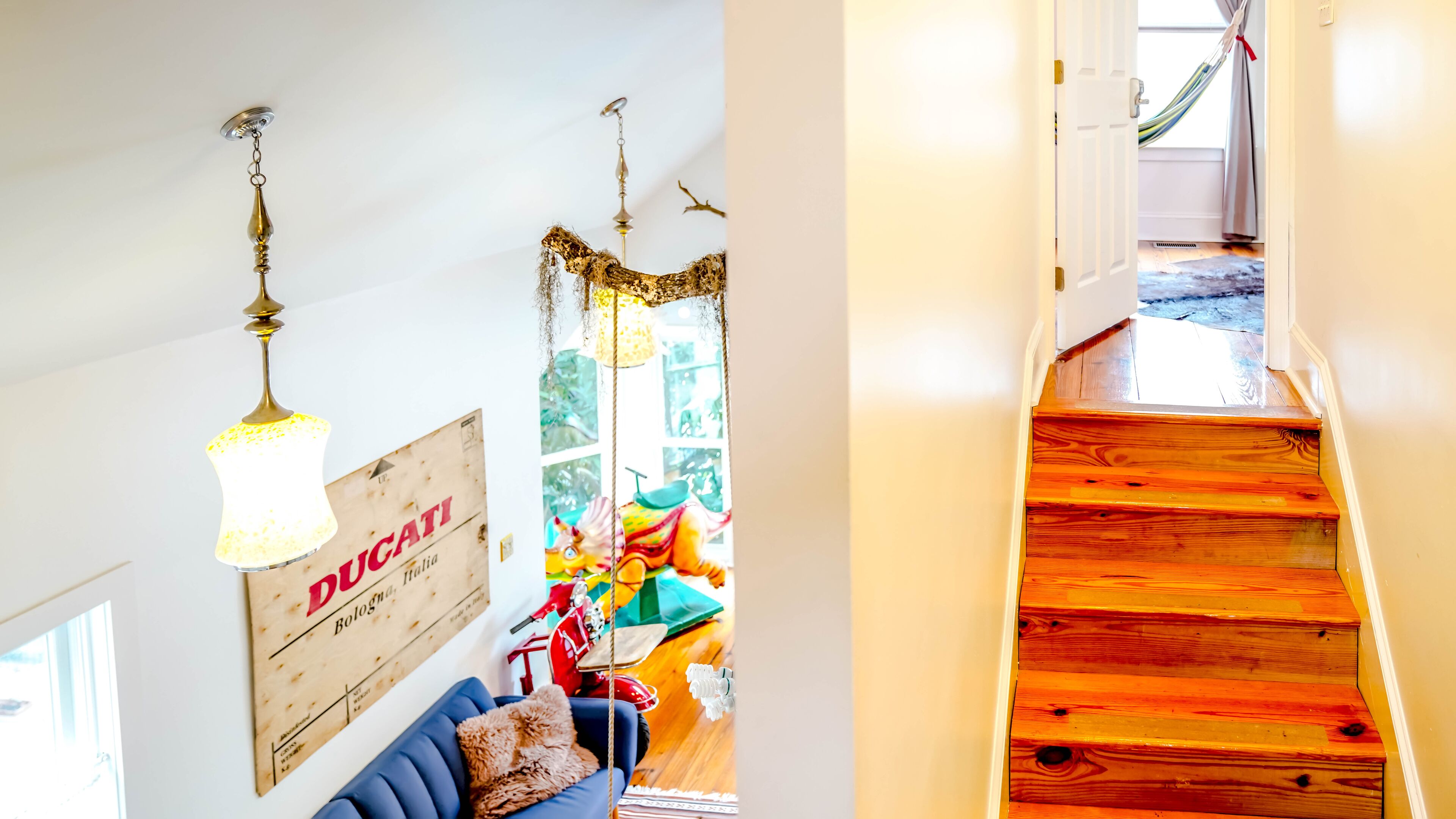 A room with a blue sofa, a wooden sign, and a hanging lamp.