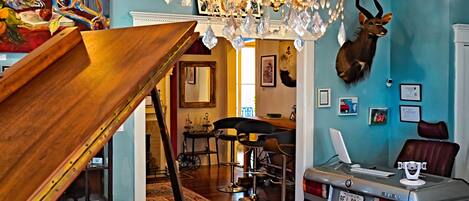 A room with a chandelier, a mounted deer head, a vintage car, and a painting on the wall.