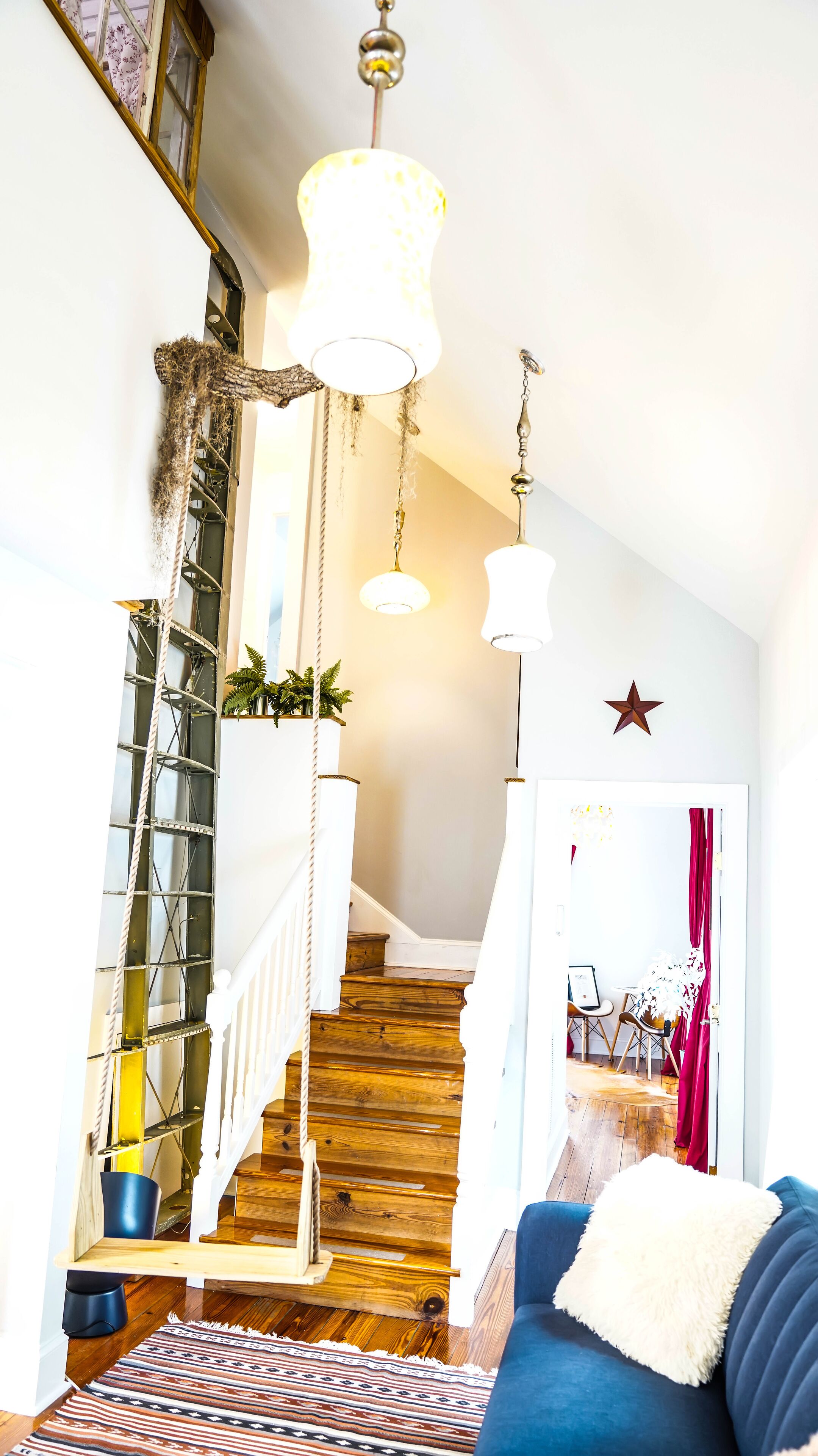 A staircase with wooden steps and a white railing, leading to a room with a blue sofa and a patterned rug.