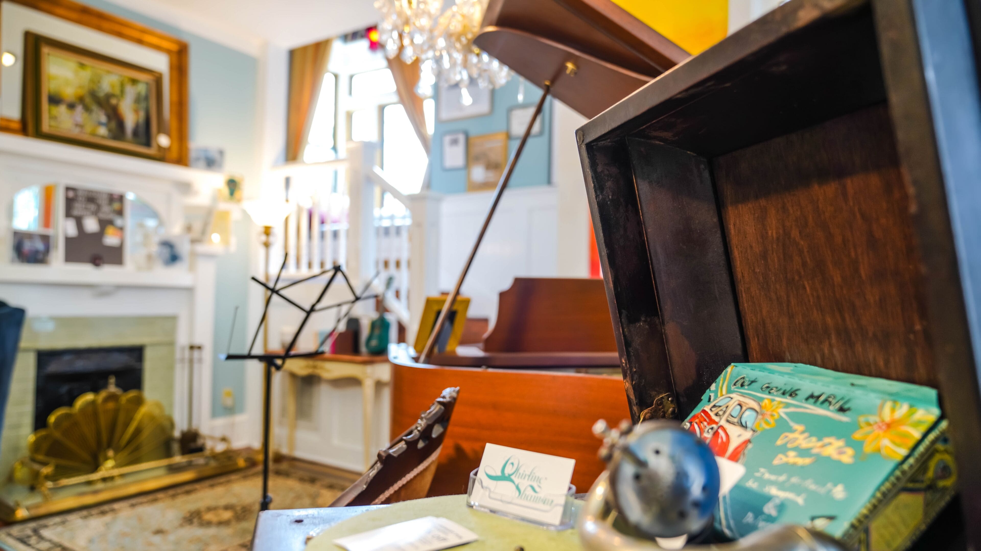Een kamer met een open haard, een piano en een tafel met een spelkaart en een klein voorwerp.