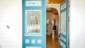 Un pasillo con una puerta azul decorada con paneles de vidrio y diseños geométricos.