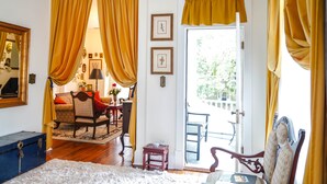 Una habitación acogedora con suelo de madera, una alfombra estampada, un sofá, una silla, una mesita pequeña y un aparador azul.