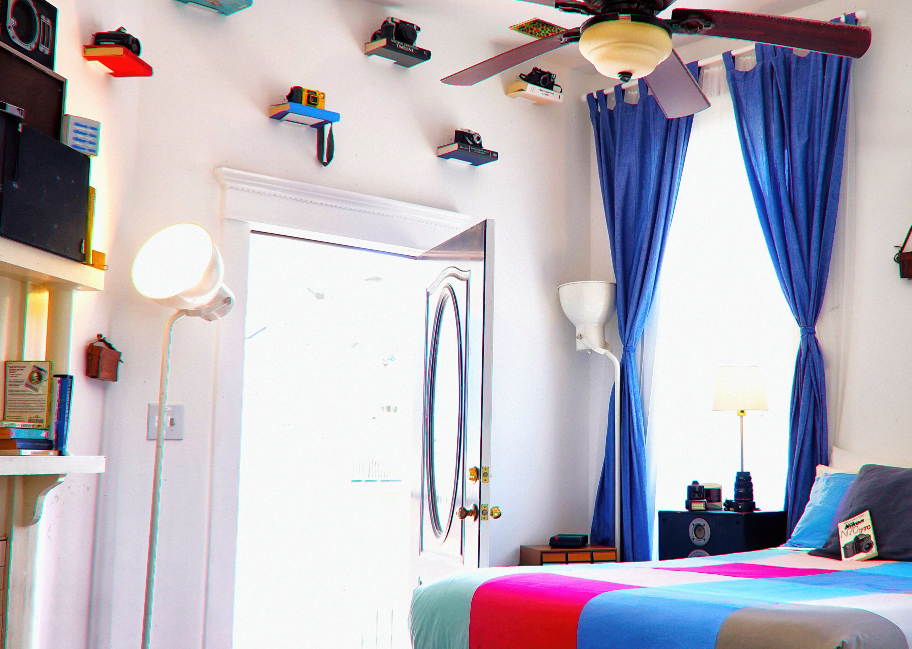 A bedroom with a bed, curtains, a ceiling fan, and various items on the walls.