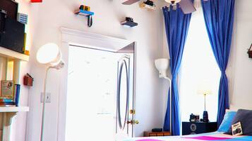 A bedroom with a bed, curtains, a ceiling fan, and various items on the walls.
