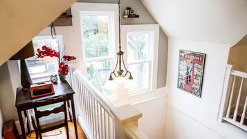 A staircase with a white railing, a wooden table with a clock and a keyboard, and a poster on the wall.