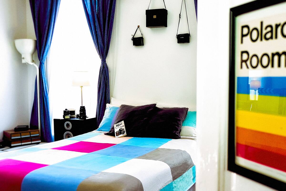 A bedroom with a bed, a nightstand, a lamp, and a framed poster on the wall.