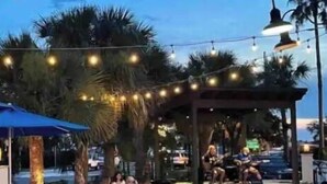 An outdoor seating area with string lights, palm trees, and a gazebo. - ISLAND VIBE ~ Close to Beach, Downtown, Egan’s Creek with Fire Pit! KQQ~2Ba (Fernandina Beach)