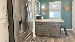 A kitchen with a stainless steel refrigerator, grey cabinets, a small island with a sink, and pendant lights. - ISLAND VIBE ~ Close to Beach, Downtown, Egan’s Creek with Fire Pit! KQQ~2Ba (Fernandina Beach)