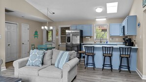 Una cocina moderna con una isla central, taburetes de bar y un refrigerador.