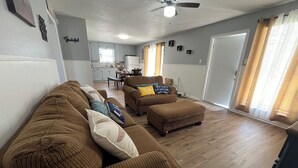 A spacious living room with a large brown sectional sofa, a matching ottoman, and a dining area in the background. - The CountryLake - First Floor for 7 Guest  (Belton)