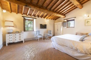 A bedroom with a bed, a dresser, a television, a window, and a chair.