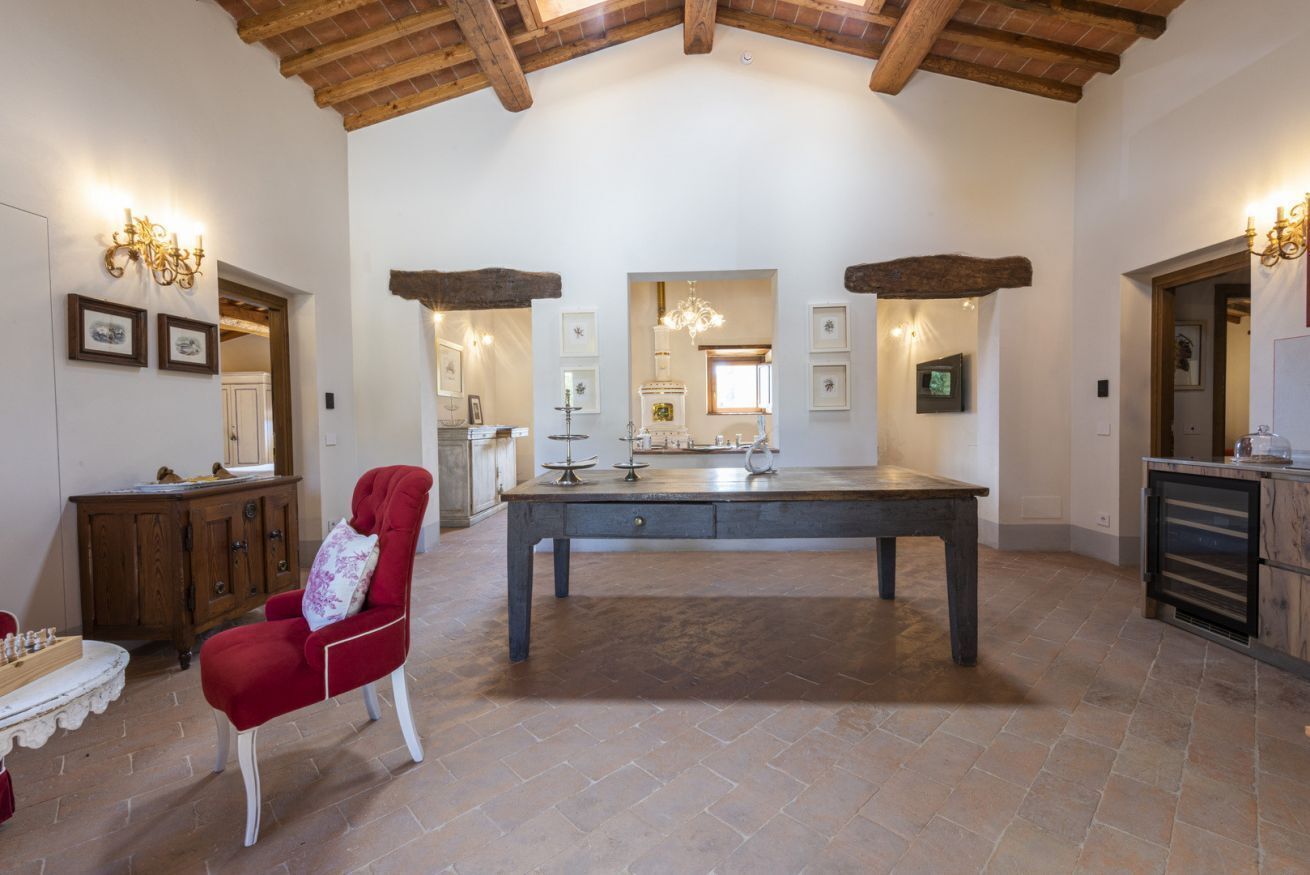 Une pièce spacieuse avec une grande table, une chaise rouge et un plafond en bois.