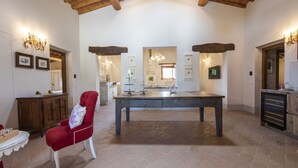 A spacious room with a large table, a red chair, and a wooden ceiling. - Villa San Cresci by MMega (Vicchio)