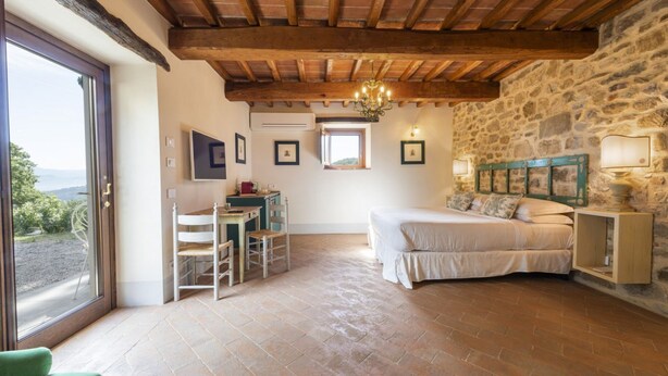 Un dormitorio con cama, escritorio, silla, candelabro y pared de piedra.